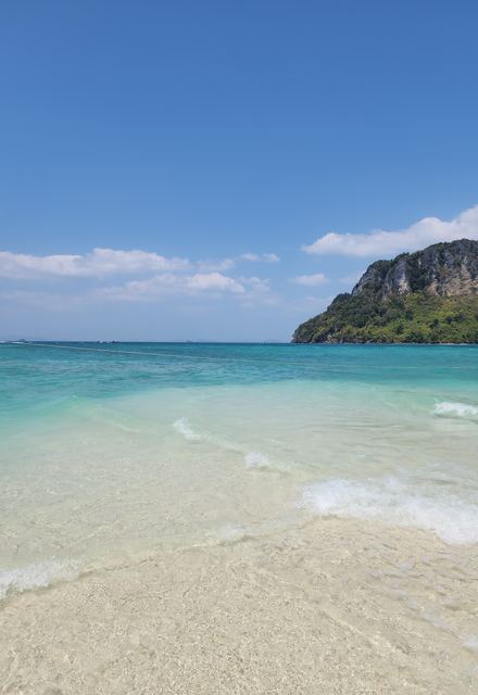 A white sand beach and turquoise water below a limestone cliff